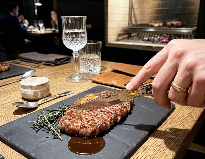 Detail of forged MOVA steel blade making a clean cut on Wagyu beef.